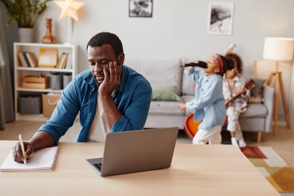 Father Working from Home with kids playing in background