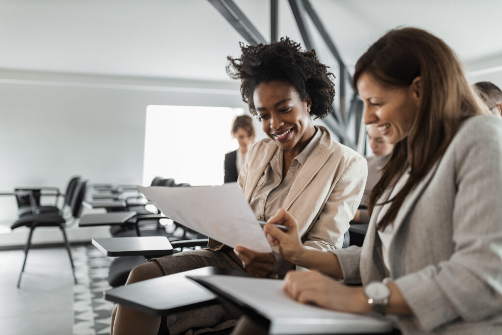 Two woman at work place, consulting each other.